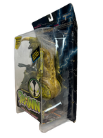 The side of a clear box containing a green dinosaur action figure with scaly skin. The text on the box says SPAWN and has blue lightning in the background..